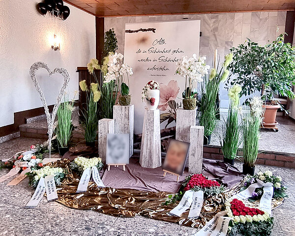 Urne auf Traueralter mit Blumenschmuck